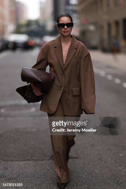 Guest is seen outside Tibi show wearing black Loewe sunnies, brown colored The Frankie Shop suit, brown leather handbag and brown leather flats on...
