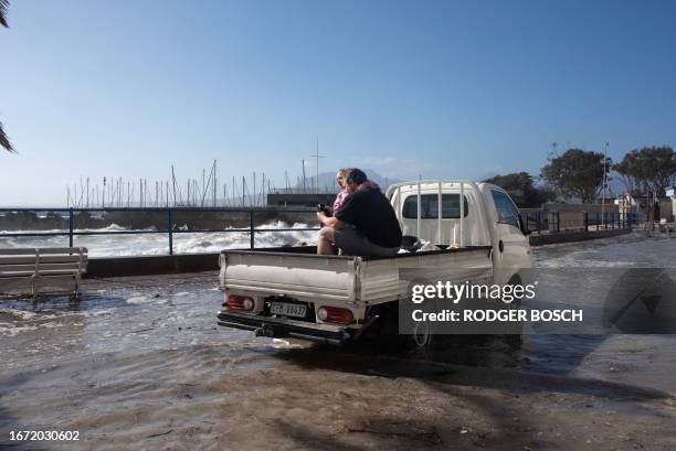 Man and a girl sit on the back of a truck to avoid seawater from unusually large waves in the coastal village of Gordon's Bay, South Africa on...