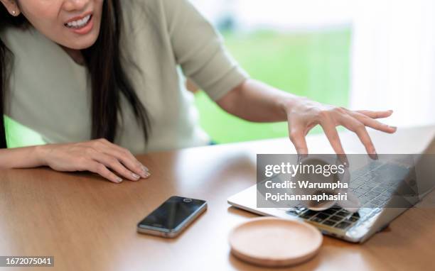 asian woman was shocked when she accidentally spilled her coffee cup on her laptop computer. - knoeien stockfoto's en -beelden