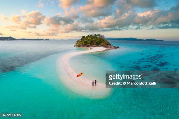 couple on idyllic tropical sandbar at sunset - palawan island stock pictures, royalty-free photos & images
