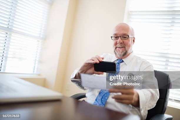 businessman depositing check via smartphone from his office - deposit slip stock pictures, royalty-free photos & images