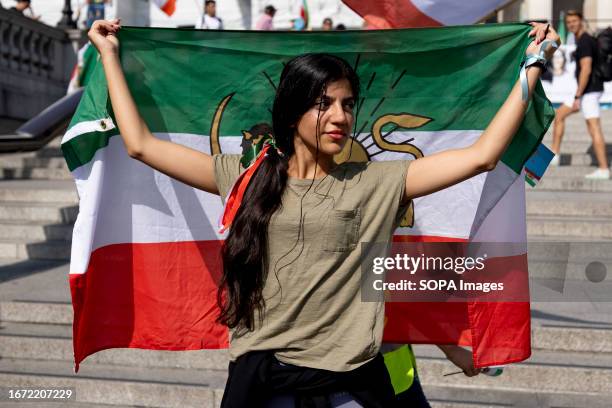 An Iranian woman protester is seen holding an Iranian flag during the demonstration in memorial of the death of Mahsa Amini under the government of...