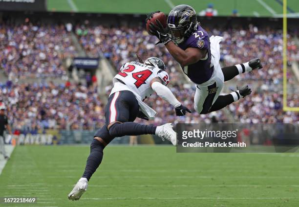 Dobbins of the Baltimore Ravens runs the ball past Derek Stingley Jr. #24 of the Houston Texans for a touchdown during the first half at M&T Bank...