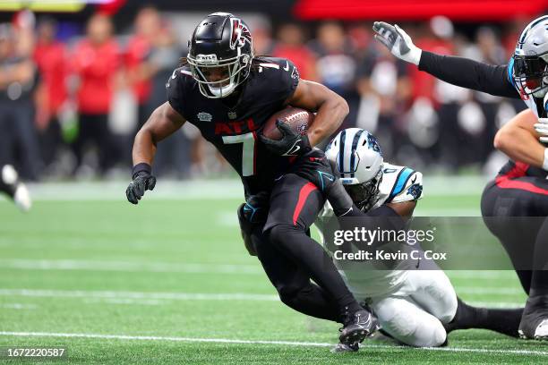 Brian Burns of the Carolina Panthers tackles Bijan Robinson of the Atlanta Falcons during the first quarter at Mercedes-Benz Stadium on September 10,...