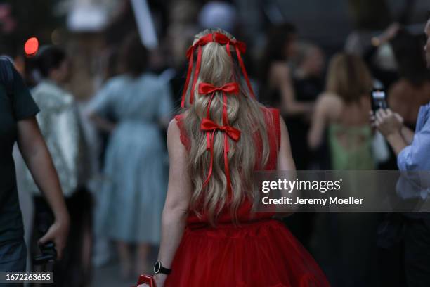 Guest is seen outside Khaite show wearing red bows in her hair, red dress on September 09, 2023 in New York City.