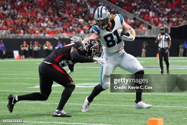 Hayden Hurst of the Carolina Panthers stiff arms Richie Grant of the Atlanta Falcons after making a catch during the second quarter at Mercedes-Benz...