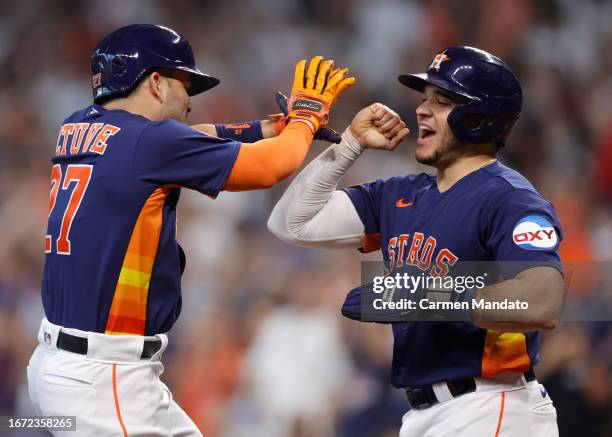 Jose Altuve of the Houston Astros high fives Yainer Diaz after hitting a two run home run during the third inning against the San Diego Padres at...