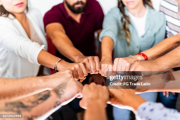 nahaufnahme eines teams beim fist bump - soziales engagement stock-fotos und bilder