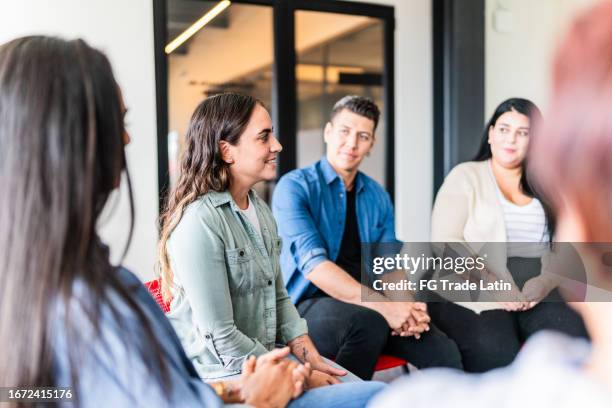 mid adult woman introducing herself in group therapy at mental health center - employee welfare stockfoto's en -beelden