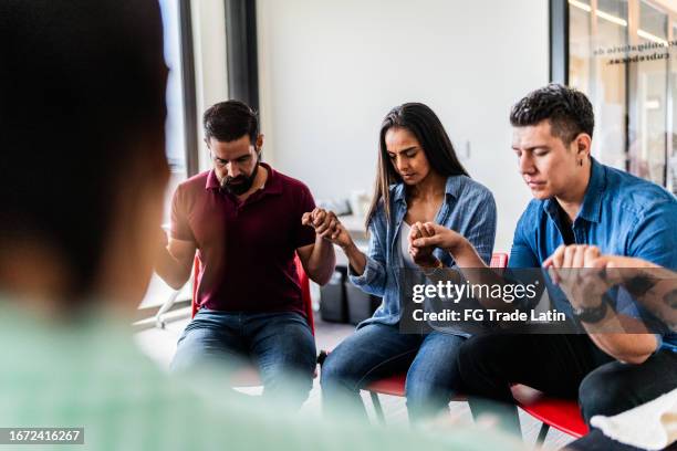 religious group praying for each other in a meeting - christianity stock pictures, royalty-free photos & images