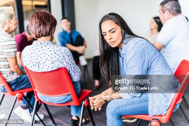triste mujer adulta durante una terapia grupal en un centro de salud mental - prejuicio fotografías e imágenes de stock