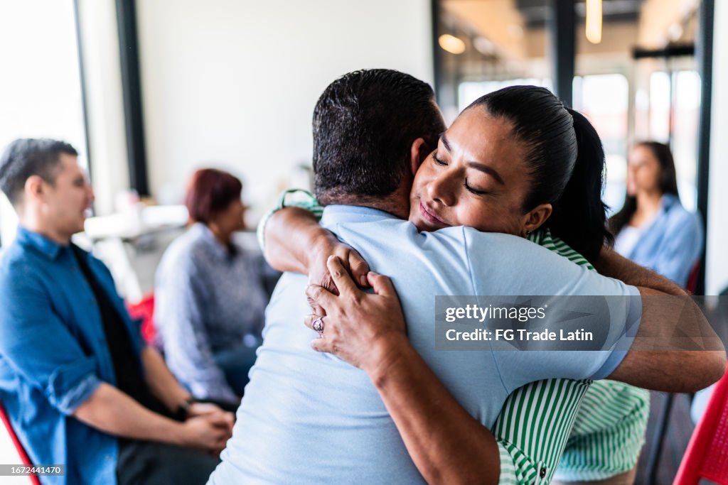 Mature couple embraced after talking in a group therapy at mental health center