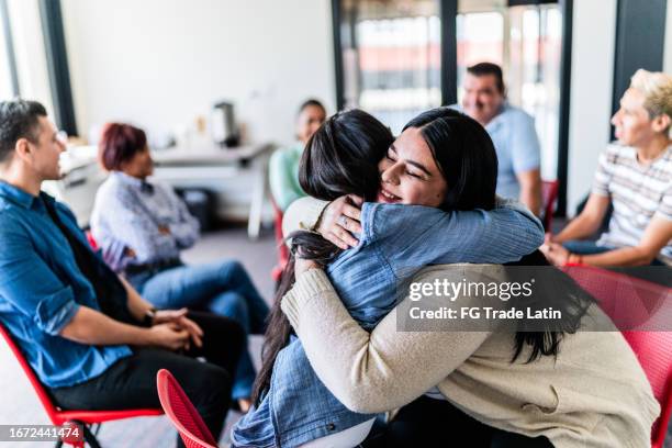 mid adult women embracing in a group therapy - love and the advice givers stock pictures, royalty-free photos & images