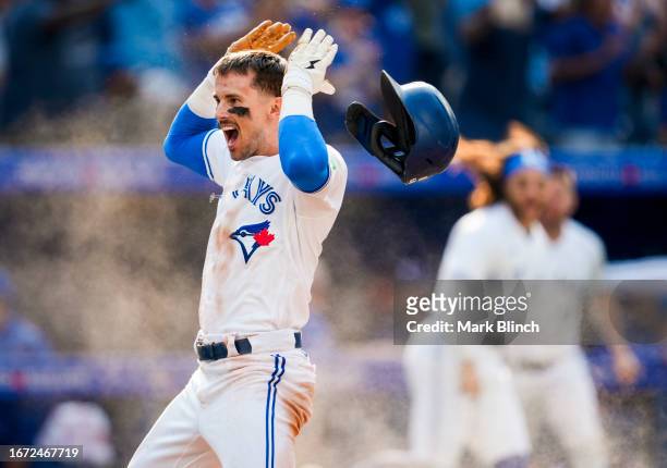 Cavan Biggio of the Toronto Blue Jays celebrates scoring the winning run against the Boston Red Sox during the ninth inning in their MLB game at the...