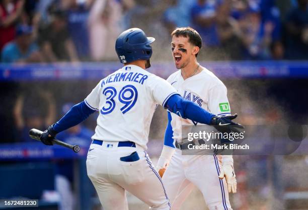 Cavan Biggio of the Toronto Blue Jays celebrates scoring the winning run with Kevin Kiermaier against the Boston Red Sox during the ninth inning in...