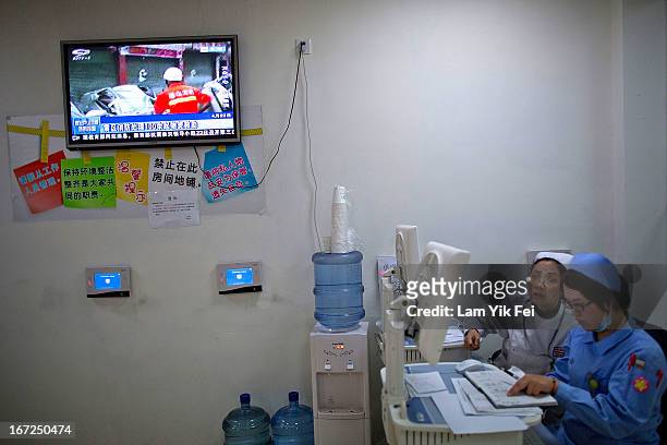 Nurses look at a computer as the television monitor boardcasts the earthquake news at the West China Hospital in Chengdu , on April 22, 2013 in...