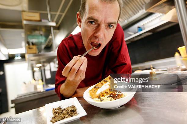 French Michelin-starred Chef David Faure is about to eat a cricket as he poses in front of a dish "Cremeux de mais, foie gras poele" in the kitchen...