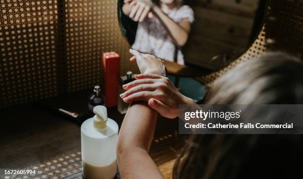 a child covers her arm with moisturiser / lotion - eczema child stock-fotos und bilder