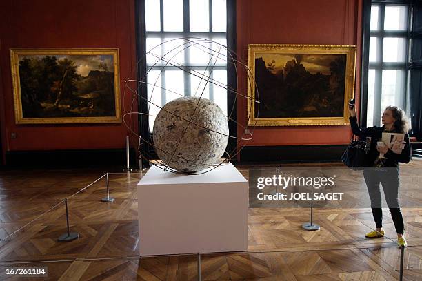 Woman takes a picture of the "Mappamondo" by Italian artist Michelangelo Pistoletto, displayed at the Louvre museum in Paris, on April 23, 2013. An...