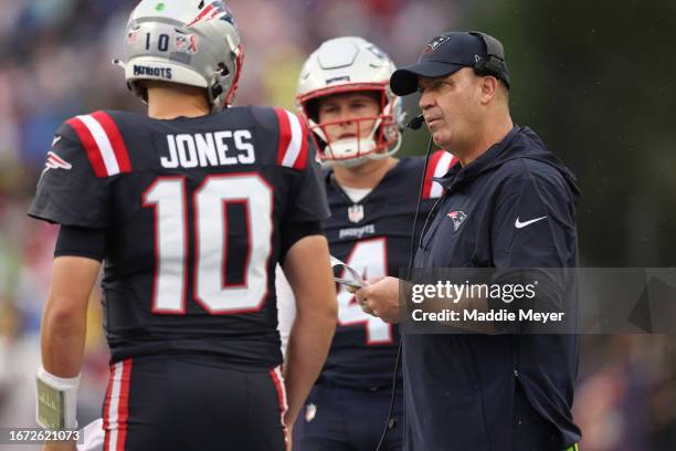 Bailey Zappe of the New England Patriots watches offensive coordinator Bill O'Brien of the New England Patriots talks to Mac Jones of the New England...