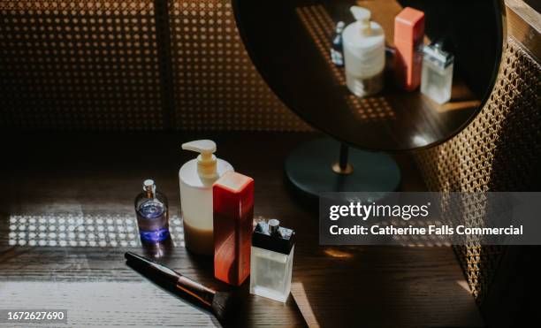 various beauty products on a dressing table in front of a vanity mirror - bolsa de cor creme fotografías e imágenes de stock