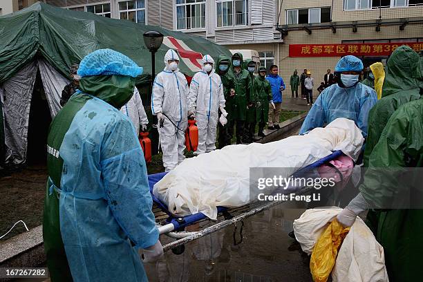 Two security guards carry the dead body of a victims at a hospital on April 23, 2013 in Lushan county of Ya An, China. A magnitude 7 earthquake hit...