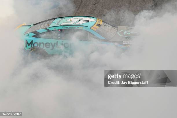 Tyler Reddick MoneyLion Toyota, driver of the 23XI Racing, celebrates with a burnout after winning the NASCAR Cup Series Hollywood Casino 400 at...