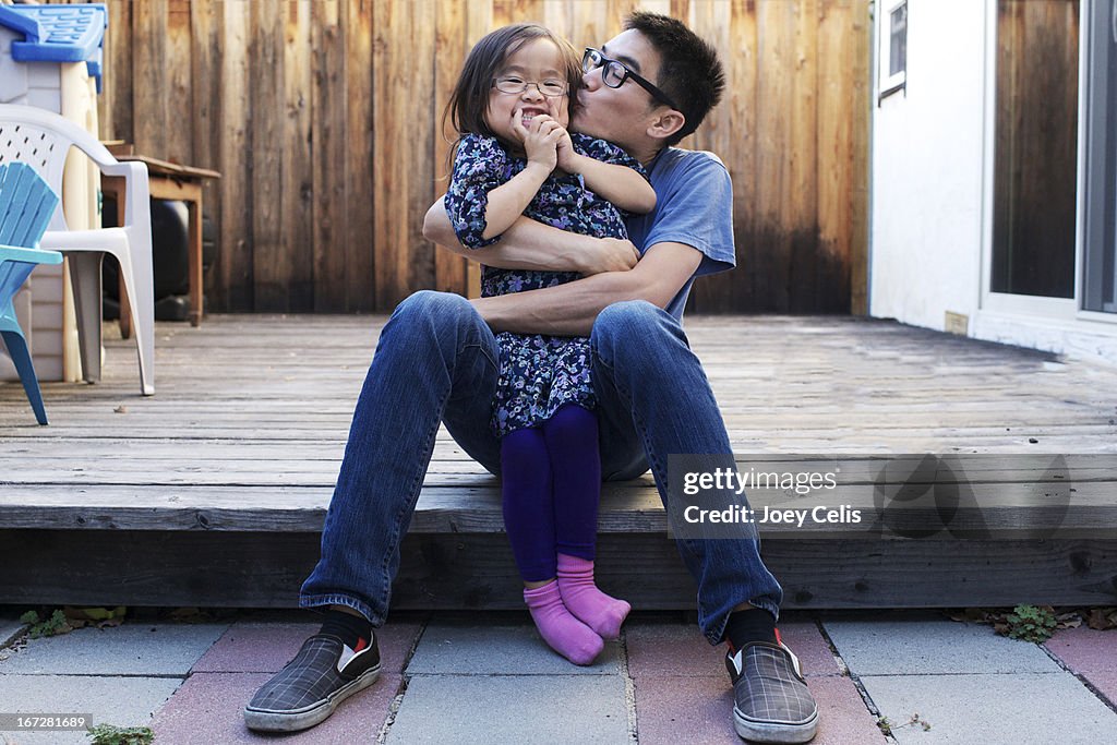 Father and daughter playfully hug and kiss