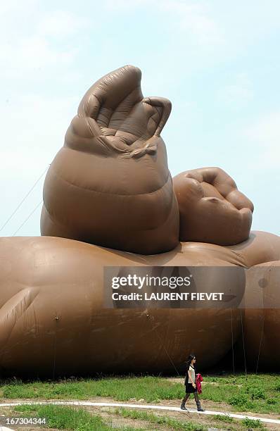 Journalist walks past a sculpture by US artist Paul McCarthy titled "Complex Pile" during a press preview of the Mobile M+: Inflation! exhibition in...