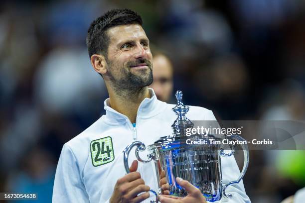 September 10: Novak Djokovic of Serbia with the winners' trophy and wearing a tracksuit representing his 24th grand slam win after his victory...