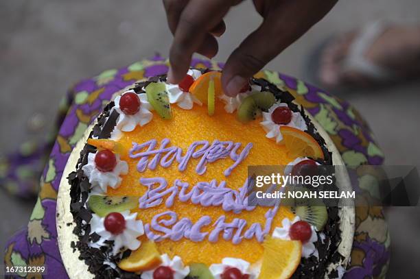 Indian cricket fans place a candle on a cake to celebrate the birthday of cricketer Sachin Tendulkar in a media organised event in Hyderabad on April...