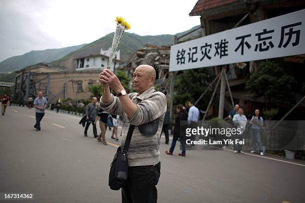 Man places flowers ans mourns for the victims of the earthquake at a park at the Beichuan town in Sichuan province on April 24, 2013 in Chengdu,...