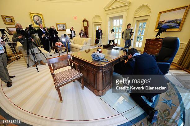 Members of the media take photographs and video inside a recreated White House Oval Office during a tour of the George W. Bush Presidential Center on...