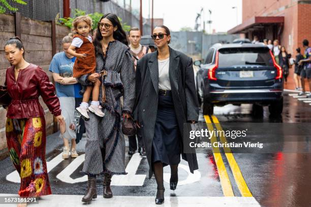 Babba Rivera with child wears grey coat & Hanna MW wears oversized grey stripped coat outside Ulla Johnson on September 10, 2023 in New York City.