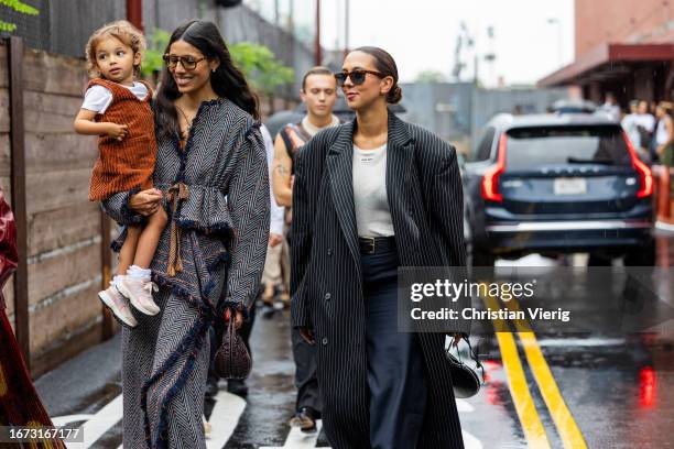 Babba Rivera with child wears grey coat & Hanna MW wears oversized grey stripped coat outside Ulla Johnson on September 10, 2023 in New York City.