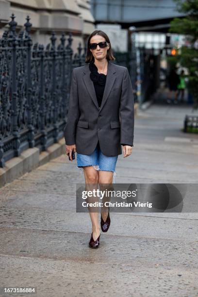 Guest wears grey blazer, denim shorts outside Area on September 10, 2023 in New York City.