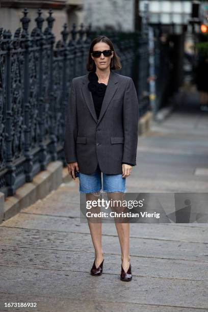 Guest wears grey blazer, denim shorts outside Area on September 10, 2023 in New York City.