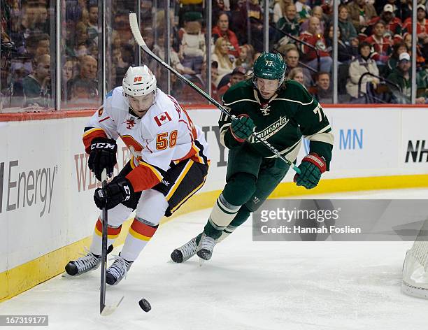 Ben Hanowski of the Calgary Flames controls the puck against Tom Gilbert of the Minnesota Wild during the game on April 21, 2013 at Xcel Energy...