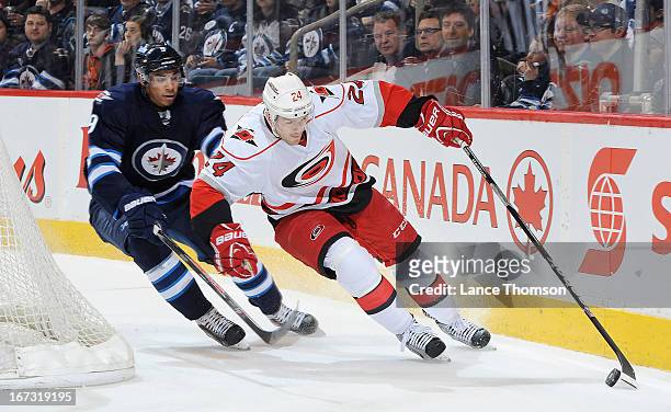 Bobby Sanguinetti of the Carolina Hurricanes plays the puck along the boards away from Evander Kane of the Winnipeg Jets during the first period at...