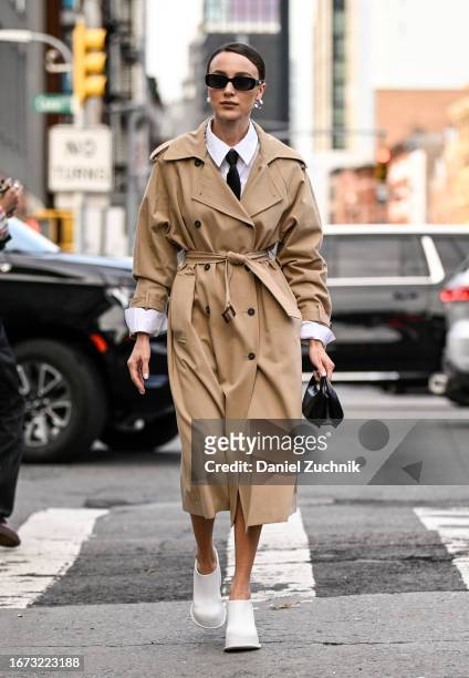 Mary Leest is seen wearing a tan trench coat, white shirt, black tie, black sunglasses, black bag and white shoes outside the 3.1 Phillip Lim show...