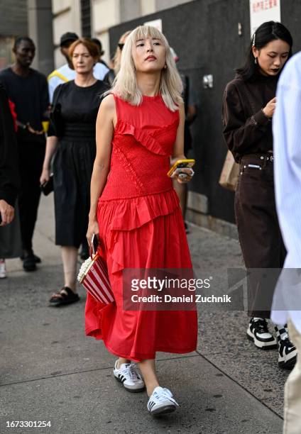 Guest is seen wearing a red dress and white Adidas sneakers with a popcorn bag outside the 3.1 Phillip Lim show during NYFW S/S 2024 on September 10,...