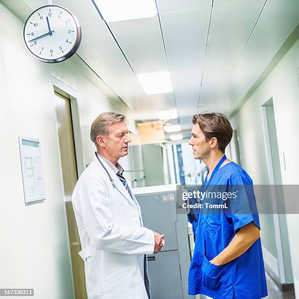 two doctors having a discussion in a corridor. - hhp5 stock pictures, royalty-free photos & images