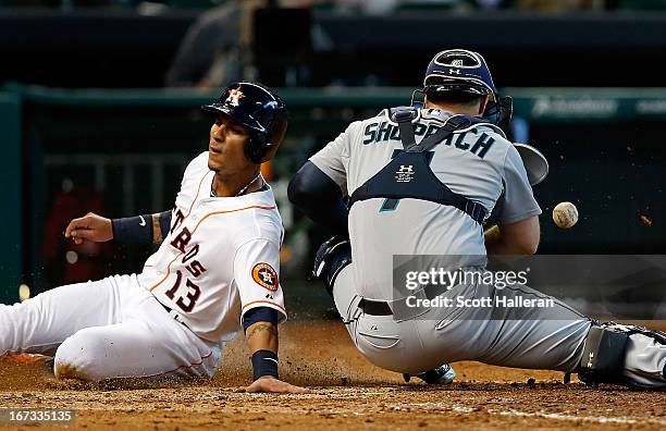 Ronny Cedeno of the Houston Astros slides into home plate under the tag of Kelly Shoppach of the Seattle Mariners in the sixth inning at Minute Maid...