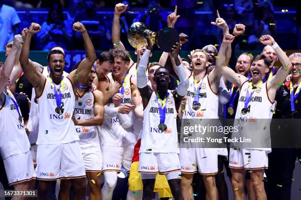 Dennis Schroder of Germany lifts the Naismith Trophy as he celebrates with teammates after the FIBA Basketball World Cup Final victory over Serbia at...