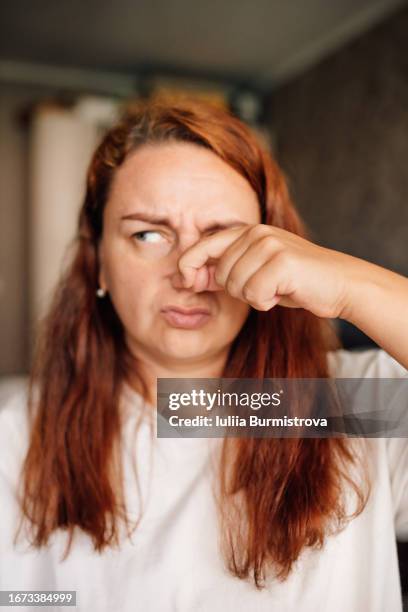 intriguing close-up of middle-aged redhead woman feeling unpleasant odor - mr stink stock pictures, royalty-free photos & images