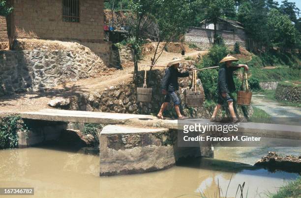 Two Chinese fishermen carry buckets towards the river, Shaoshan, China, May 1980