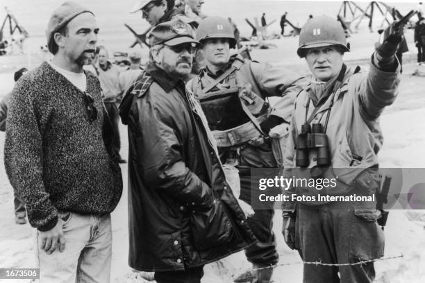 Director Steven Spielberg and actor Tom Hanks listen as an unidentified man points with a walkie-talkie on the set of the film, 'Saving Private...