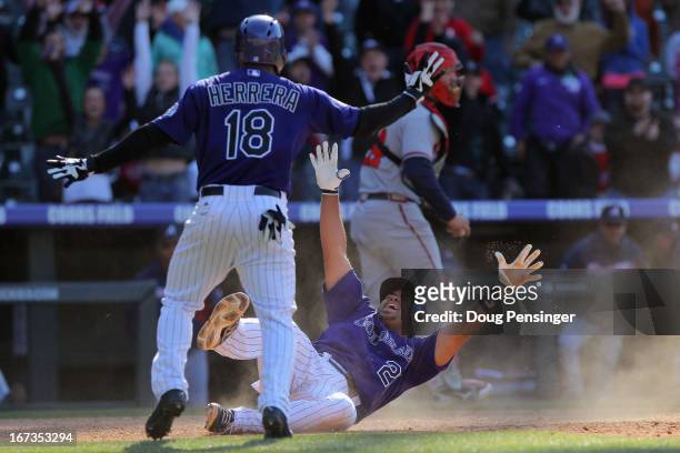 Wilin Rosario of the Colorado Rockies slides home with the winning run and celebrates with Jonathan Herrera of the Colorado Rockies on a single by...