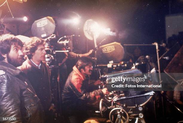 American director Tobe Hooper lenses a shot behind the camera as producer and co-director Steven Spielberg and other crew members stand by on the set...