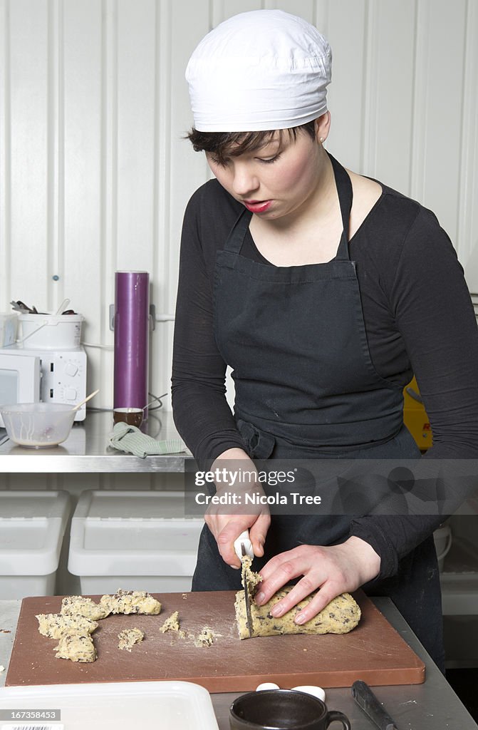 A young baker cutting up cookie dough